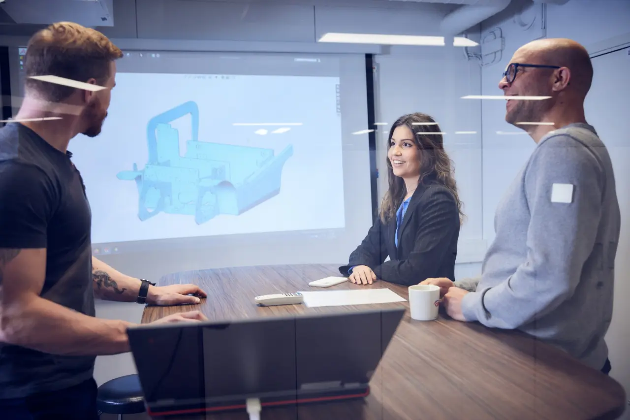 Möte i konferensrum där en CAD-modell av en trucksmast presenteras på storskärm