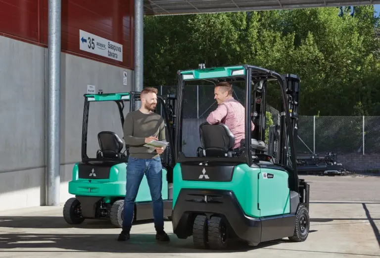 Två män i samtal vid Mitsubishi Edia motviktstruckar utanför lastintag – Logisnext