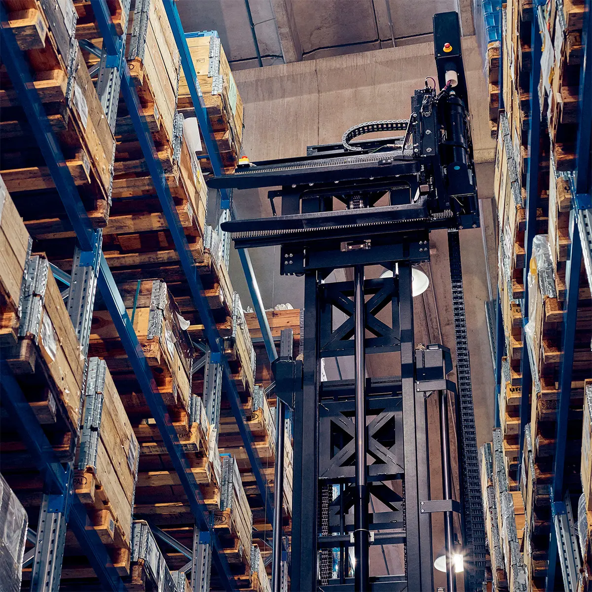 Vy underifrån på en automatiserad smalgångstrucks lyftmast mellan höga pallställ